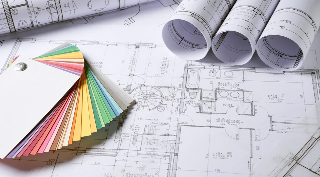Color swatches fanned out on top of architectural blueprints, with several rolled-up plans placed nearby—perfect inspiration for an Essex architect working on party wall projects.